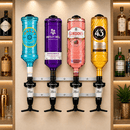 A wall-mounted bar dispenser rack holding four oversized liquor bottles in turquoise, purple, pink, and gold, with black spouts labeled 25ml. The setup is shown against a warm beige shelving background with bottles and a plant visible.