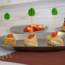 Three small sandwiches with leaf and carrot decorations on toothpicks on a tray.