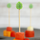 Fruit skewer with orange, red, and strawberry pieces on a gray surface.