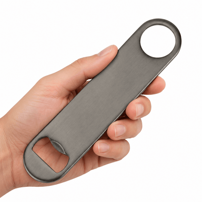 A hand holding a long, slim gunmetal bottle opener with a circular ring at one end and a bottle-opening slot at the other, shown against a plain white background.