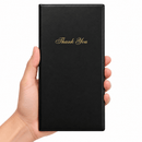 A hand holding a slim black rectangular bill presenter with elegant gold 'Thank You' script on the front, set against a plain white background.