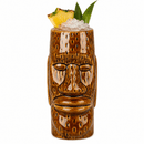 A brown ceramic tiki mug shaped like a moai face, filled with crushed ice and garnished with a pineapple slice and green leaves, on a white background.