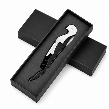 A black and silver corkscrew tool presented in an open black gift box with two additional closed boxes behind it on a white background.