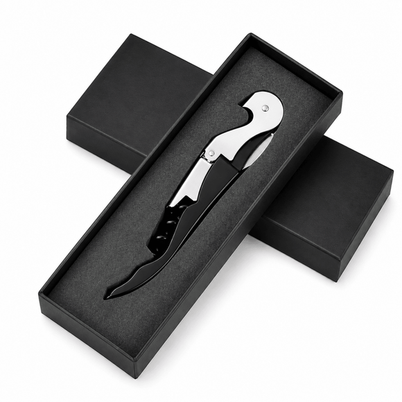 A black and silver corkscrew tool presented in an open black gift box with two additional closed boxes behind it on a white background.