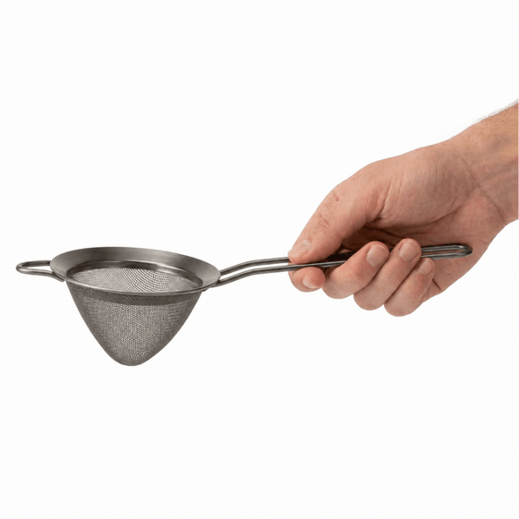A hand holding a gunmetal stainless steel fine mesh strainer with a long handle against a plain white background.
