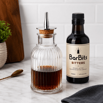 BarBits Bitters bottle and glass container on a marble surface with a white tiled wall background.