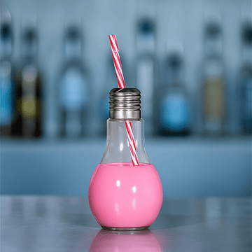 Pink drink in a light bulb-shaped glass with a straw against a blurred bar background