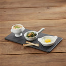 Three small white bowls with different dishes on a dark slate tray, placed on a wooden surface.