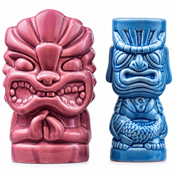Two ceramic tiki-style mug or cup figurines on a white background: one in glossy pink and one in glossy blue, both with carved facial features and textured bodies.