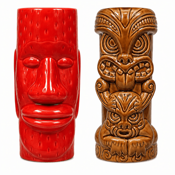 Two ceramic tiki mugs shown side by side on a plain white background. The mug on the left is glossy red with a stylized face design.