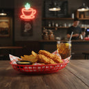 Fried chicken and fries in a red basket with a glass of iced tea on a wooden table, neon coffee cup sign in the background.