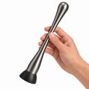 A hand holding stainless steel gunmetal slim cocktail muddler 23cm a black rubber base against a plain white background.