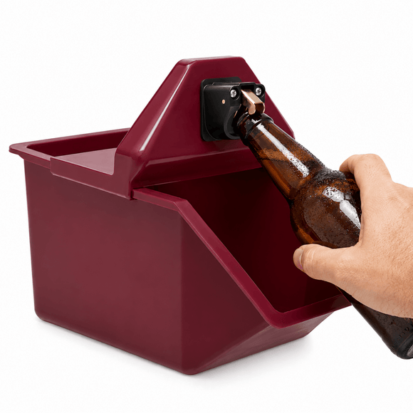 A hand holding a brown glass beer bottle against a dark red plastic bottle opener mounted on a wall, shown on a white background.