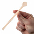 Hand holding a wooden stirrer against a white background
