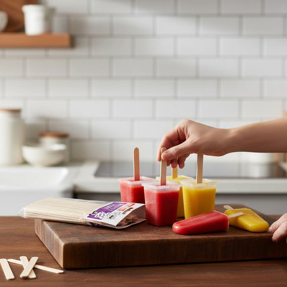 Person making popsicles on a wooden cutting board in a kitchen.