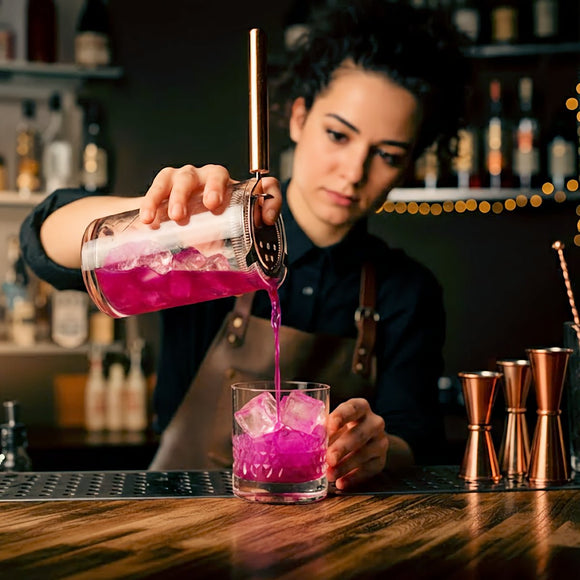 Bartender using a stainless steel Hawthorne cocktail strainer to pour a cocktail into a glass