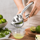 Person using a manual lime squeezer to extract juice into a small glass bowl on a wooden surface.